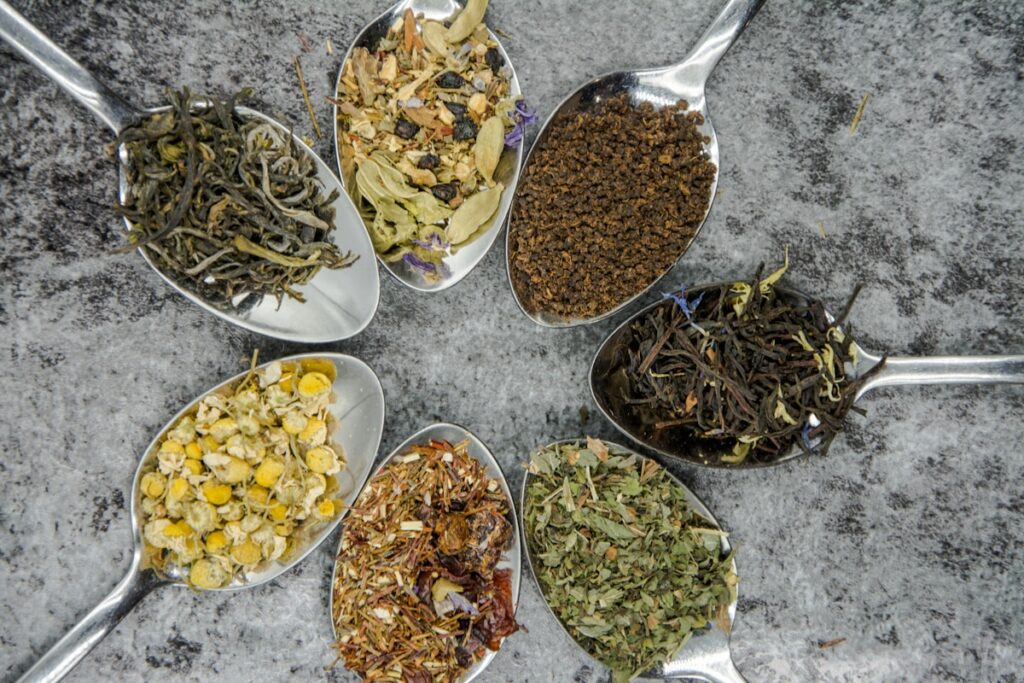 seven different spices and herbs on gray stainless steel spoons